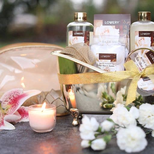 Bath and body gift set with candles and flowers on a table