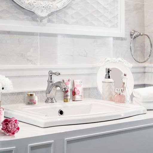 Bathroom sink with decorative elements and toiletries on a light-colored tiled wall.